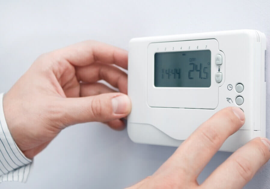 Hands Adjusting thermostat on wall